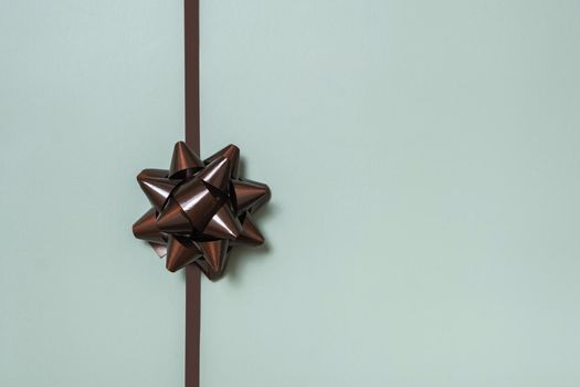 Festive brown gift bow for decorating a gift top view on a colored background.