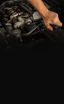 Auto mechanic working on car engine in mechanics garage. Repair service. Close-up shot, vertical view. Free space for text, copy space