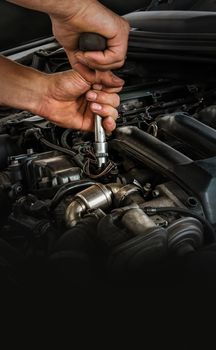 Auto mechanic working on car engine in mechanics garage. Repair service. Close-up shot, vertical view. Free space for text, copy space