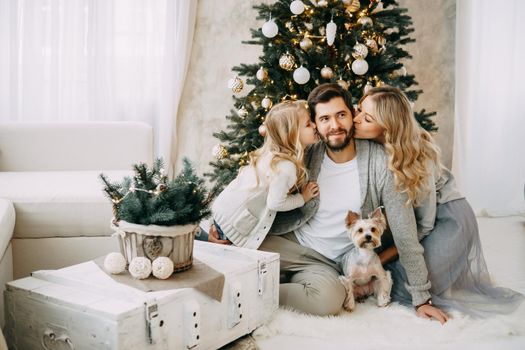 Happy family: mom, dad and pet. Family in a bright New Year's interior with a Christmas tree.