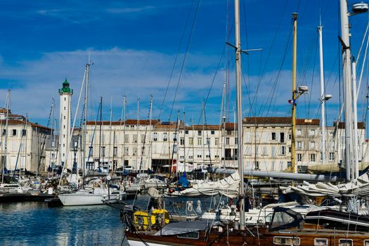 View of the harbour of the French city of La Rochelle with yachts in the foreground and the Les Phares lighthouse in the background with blue sky and sunny summer day.