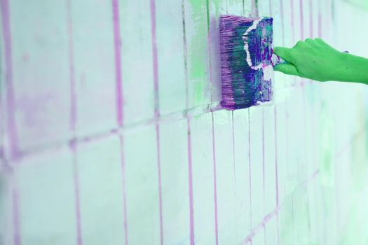 the process or skill of applying a substance to something so as to change its original color. Brush painting dyeing surface with green paint and green rubber gloves