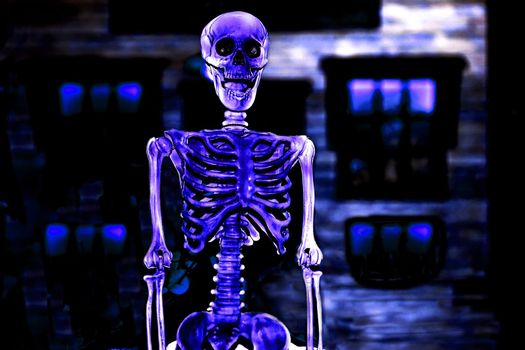 the night of October 31, the eve of All Saints' Day, commonly celebrated by children who dress in costume and go door asking for candy. Blue silver violet poisonous halloween skeleton in dark room