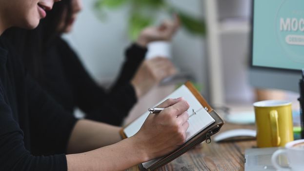 Young man sitting in creative office and making some information on notebook.