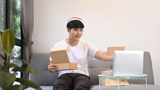 Happy young man showing Christmas present during video call with his family.