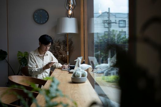 Young asian man sitting in cafe and using smart phone.