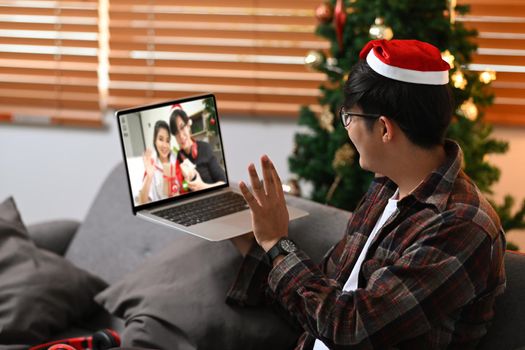 Man red Santa hat having video call for celebrating holiday with his family.