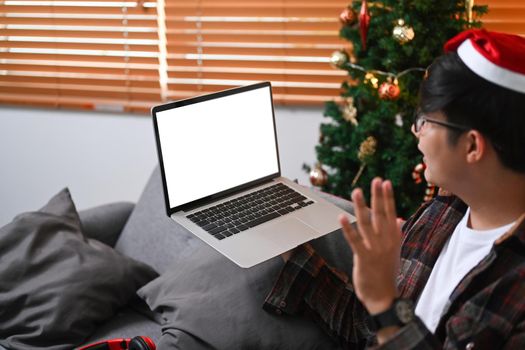 Happy man having video call via laptop computer on Christmas Eve at home.