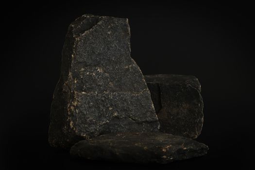 Rock podium on the black background. Stone podest for product, cosmetic presentation. Creative mock up. Pedestal or platform for beauty products