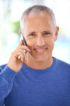 Keeping up with the family news. Portrait of a smiling mature man on the phone