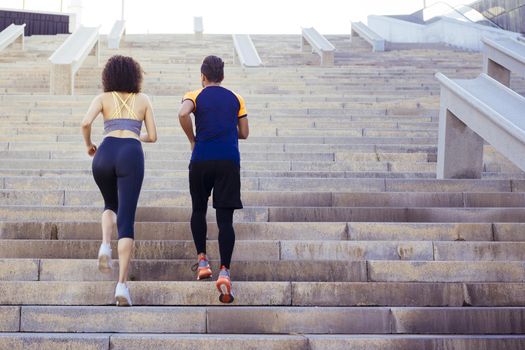 young woman and man running upstairs on city stairs, fitness, urban sports workout and healthy lifestyle concept, copy space for text