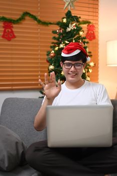 Happy asian man greeting someone during video call on laptop computer at home.