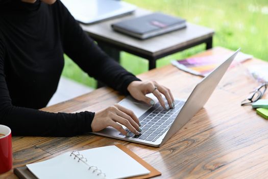 Cropped shot female designer working with laptop computer at her office desk.