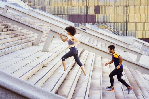 young latin sports woman and afro american man running up stairs in the city. fitness, urban sports workout and healthy lifestyle concept, copy space for text