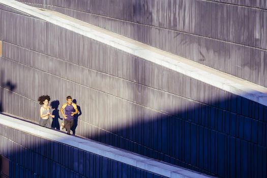 sports woman and man running on the city street in modern environment of walls. fitness, urban sports workout and healthy lifestyle concept, copy space for text