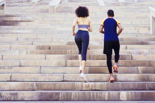 young runners couple running upstairs on city stairs, fitness, urban sports workout and healthy lifestyle concept, copy space for text