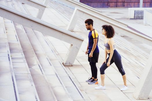 interracial couple of runners preparing to train on the city stairs. fitness, urban sports workout and healthy lifestyle concept, copy space for tex