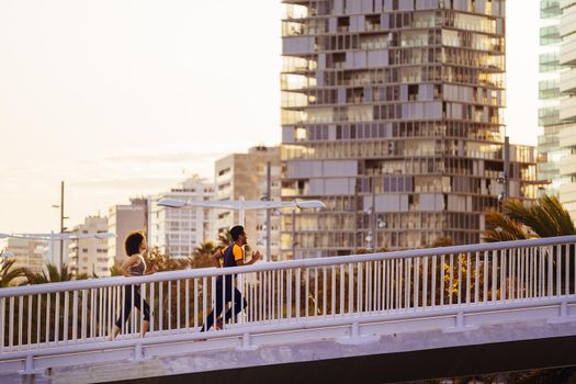 athletic sporty couple jogging together at sunset in the city bridge with buildings in the background. urban sports workout in couple and healthy lifestyle concept