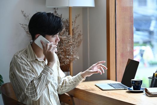 Smart businessman talking on mobile phone while sitting in his office room.