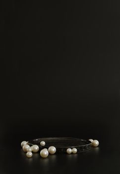 Black podium on the black background with pearls. Podium for product, cosmetic presentation. Creative mock up. Pedestal or platform for beauty products. Minimalist design, vertical view.