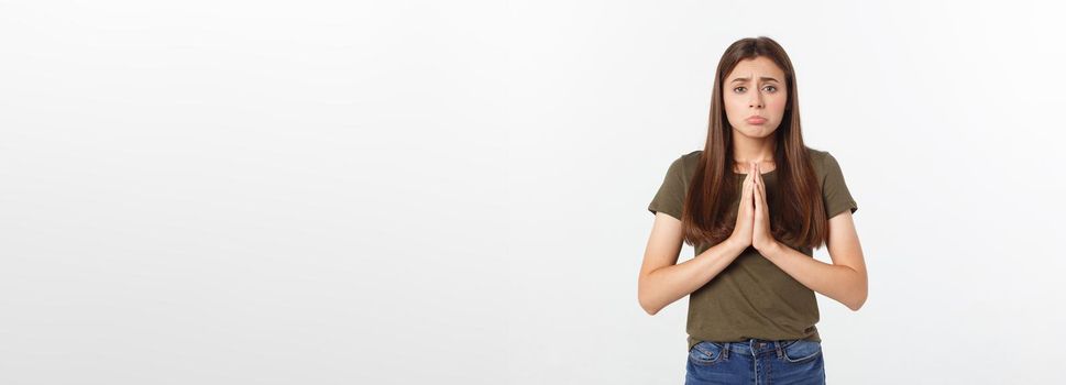 Beautiful young woman in casual clothes holding hands together and praying, isolated on white