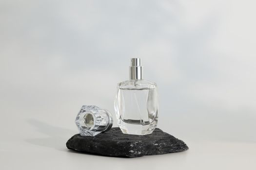 Unbranded perfume bottle standing on stone podium. Perfume presentation on the white background. Mockup. Trending concept in natural materials. Women's and men's essence. Natural cosmetic