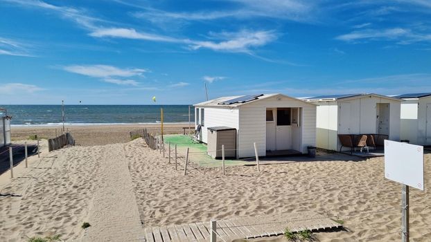 View from dunes on North Sea city beach on a sunny summer weekend. Typical pavilions. Path to North sea beach. Zandvoort, Netherlands.