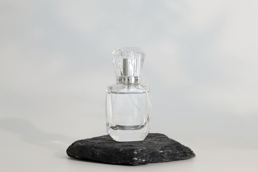 Unbranded perfume bottle standing on stone podium. Perfume presentation on the white background. Mockup. Trending concept in natural materials. Women's and men's essence. Natural cosmetic