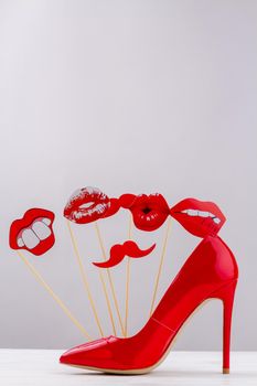 Red high heel shoe on white background. Funny cartoon lips and moustaches.