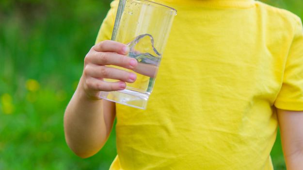little boy drinking water with a glass in the park.Selective focus
