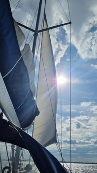 Sailing yacht boat on seawater at sunrise with sun flare and outdoor lifestyle.