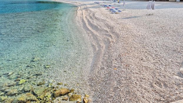 Beautiful shore of the Adriatic Sea. Bay view with beach and deck chairs. Sunrise.