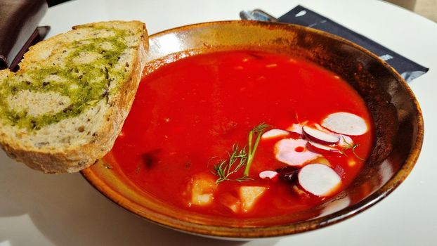 Hot rich fresh borscht, beet soup with vegetables on a plate.