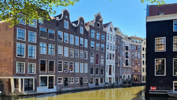 Channel in Amsterdam Netherlands. Houses river Amstel landmark. Old European city summer landscape.