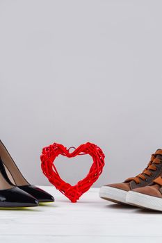 Still life of mens and womens shoes and red heart. Vertical shot copy space.