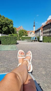 Slender tanned female legs in white shoes, selfie.