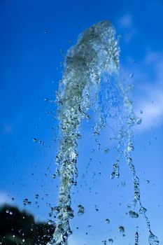 A jet of fountain water on a blue sky background. taken on a short shutter speed