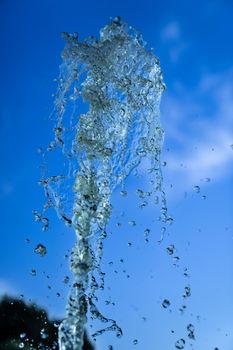 A jet of fountain water on a blue sky background. taken on a short shutter speed