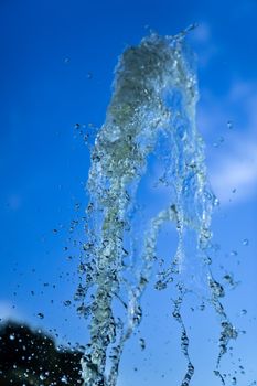 A jet of fountain water on a blue sky background. taken on a short shutter speed