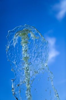 A jet of fountain water on a blue sky background. taken on a short shutter speed