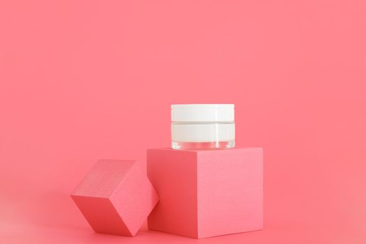White unbranded cosmetic cream jar standing on pink podium. Skin care product presentation on the pink background. Trendy mockup. Skincare, beauty and spa