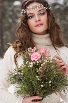 Beautiful bride in a white dress with a bouquet in a snow-covered winter forest. Portrait of the bride in nature.Beautiful bride in a white dress with a bouquet in a snow-covered winter forest. Portrait of the bride in nature.