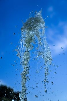 A jet of fountain water on a blue sky background. taken on a short shutter speed