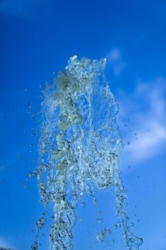 A jet of fountain water on a blue sky background. taken on a short shutter speed