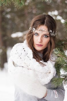 Beautiful bride in a white dress with a bouquet in a snow-covered winter forest. Portrait of the bride in nature.