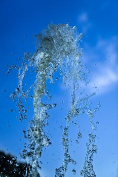 A jet of fountain water on a blue sky background. taken on a short shutter speed