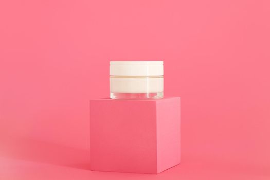 Cosmetic cream packaging standing on pink podium. Cream presentation on the pink background. Mockup