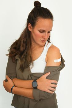 Coronavirus vaccination advertisement. Vaccinated woman showing arm with plaster bandage after Covid-19 vaccine injection. Concept of recommended inoculation, vaccination, vaccinated patient, vaccine