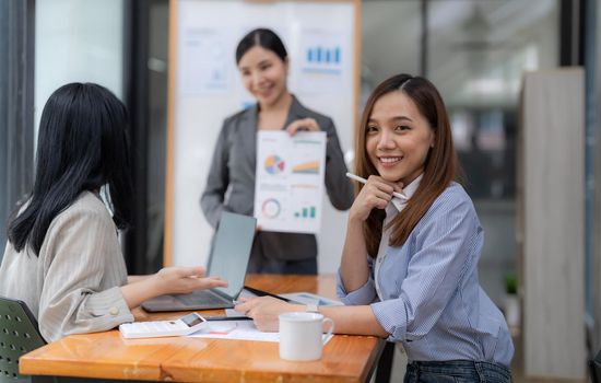 Portrait of businesswoman smart casual wear looking at camera and smile with digital table in modern office workplace. Young Asia lady standing relax in contemporary meeting room