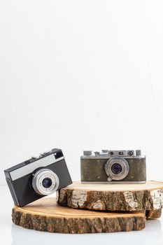 Two retro photo cameras on wooden boards. Concept of mens and womens cameras. Vertical shot isolated on white.